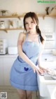 A woman in a blue and white apron standing in a kitchen.